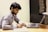 A focused entrepreneur working on a business plan at a sleek desk with notes and a laptop.