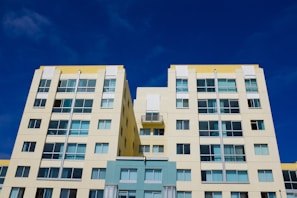 Modern residential building with green and yellow accents under a clear sky.