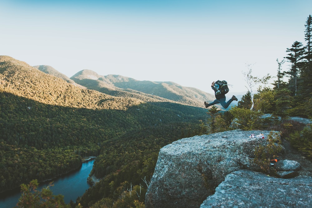 time lapse photo of person jumping from cliff within mountain range