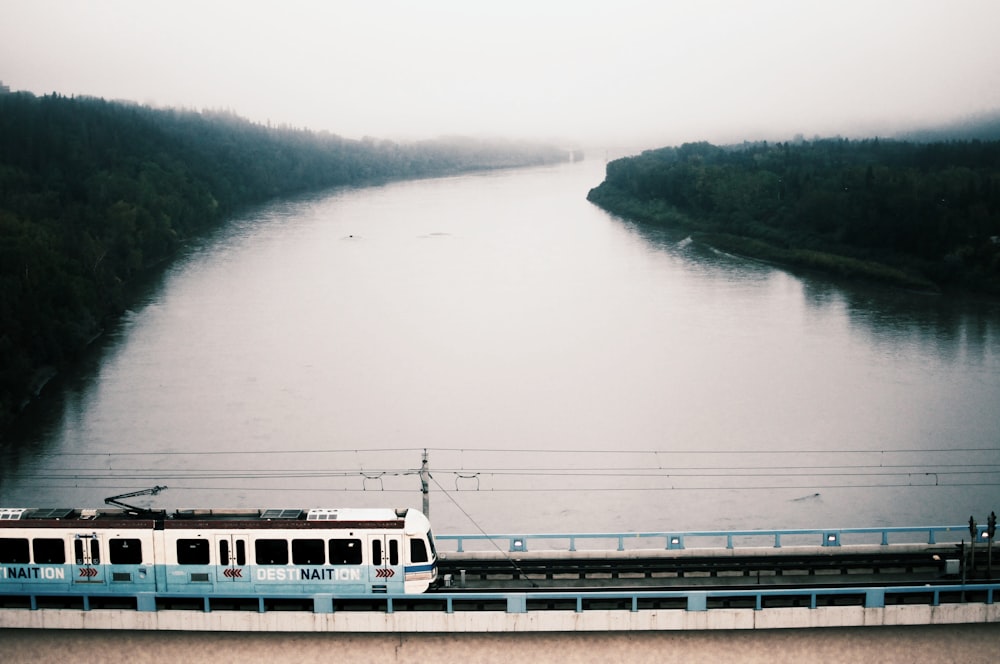 Trem branco na ponte sobre o rio durante o dia