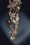 An elegant piece of jewelry featuring floral designs with intricate metalwork and adorned with pearls and gemstones. The craftsmanship is delicate, with attention to detail in the arrangement of the flower petals and leaves.