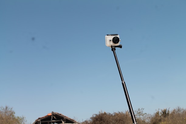 A close-up of a sleek Zanazi selfie stick held by a smiling person outdoors.