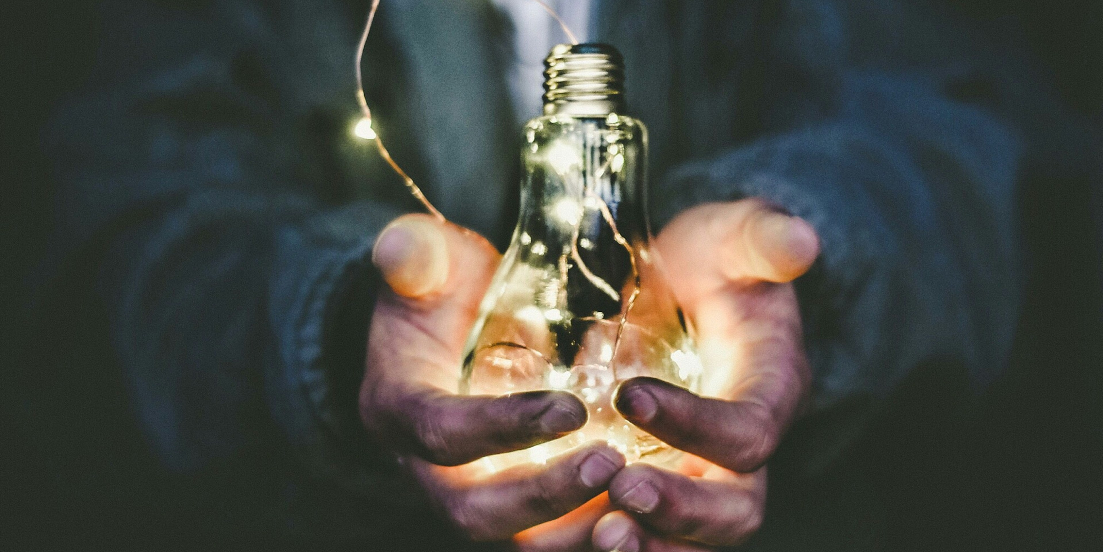 man holding an incandescent light bulb