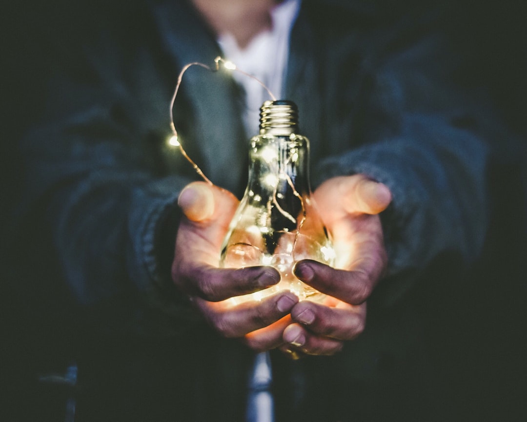 Holding a light bulb in hands - Top Digital Innovation Consultancy Guide - Photo by Riccardo Annandale | de Paula Consultants