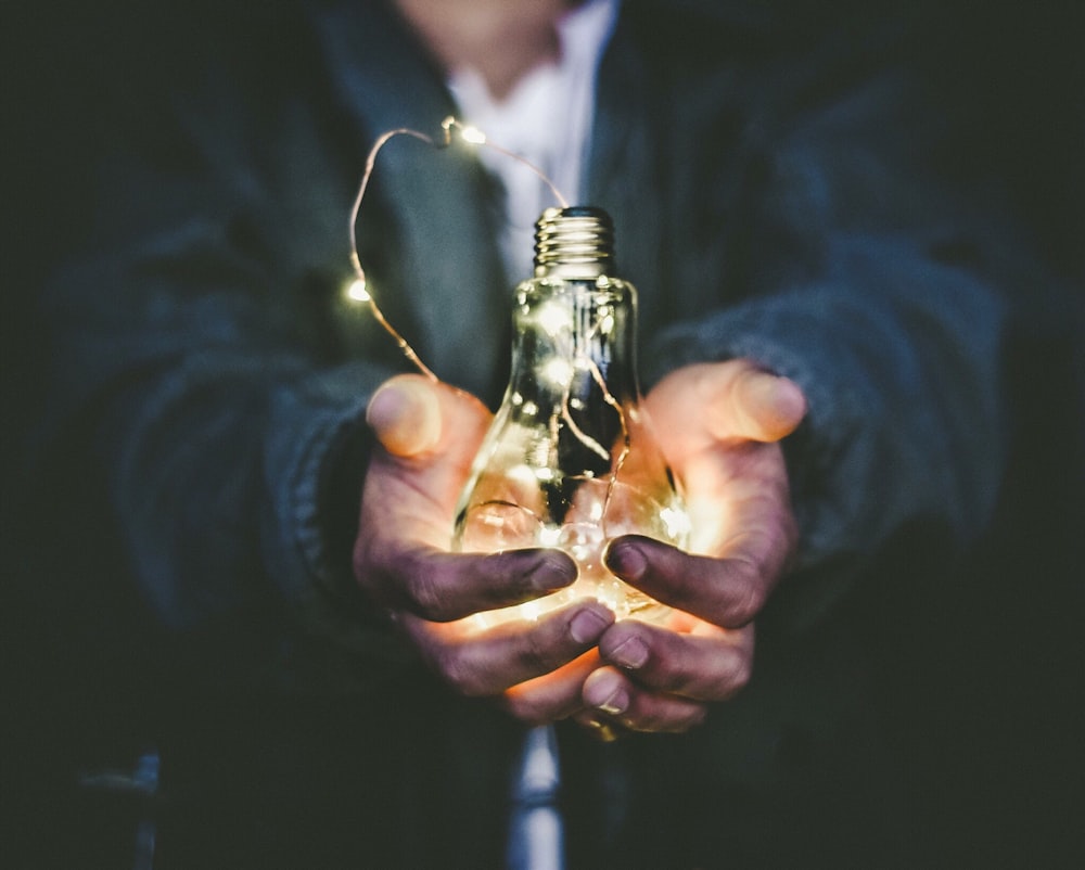 uomo che tiene la lampadina a incandescenza