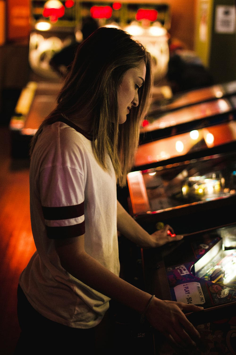 woman in white and black shirt standing in front of arcade machine
