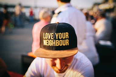 man wearing black cap with love your neighbour print during daytime