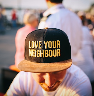 man wearing black cap with love your neighbour print during daytime