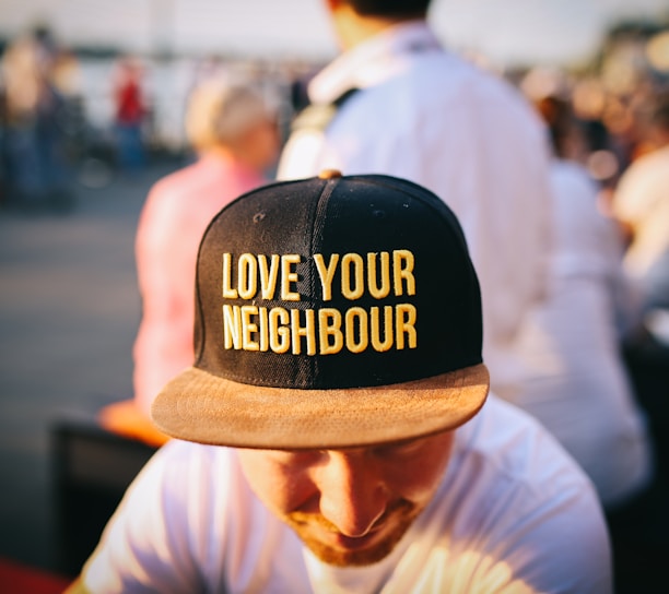 man wearing black cap with love your neighbour print during daytime