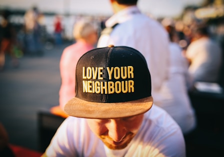 man wearing black cap with love your neighbour print during daytime