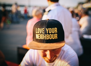 man wearing black cap with love your neighbour print during daytime