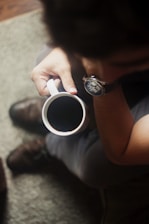 person with wristwatch holding a mug of coffee