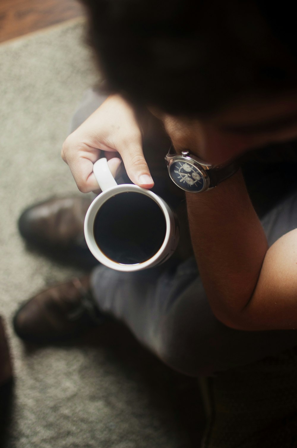 Person, die auf der Couch sitzt und Kaffeetasse hält