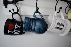 three hanged assorted-color ceramic mugs