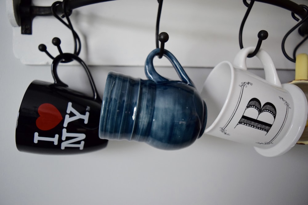 three hanged assorted-color ceramic mugs