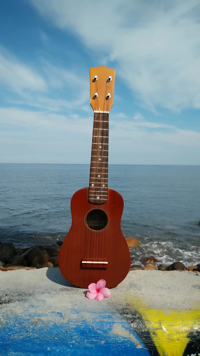 A cozy ukulele resting on a sunlit beach towel with palm trees swaying gently in the background.