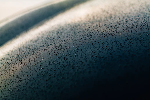 A close-up of dewy skin glistening softly in natural morning light, with droplets of water highlighting the texture.