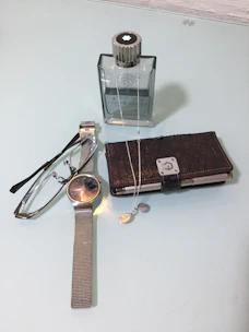 A sleek leather belt rolled neatly beside a vintage watch and keys.