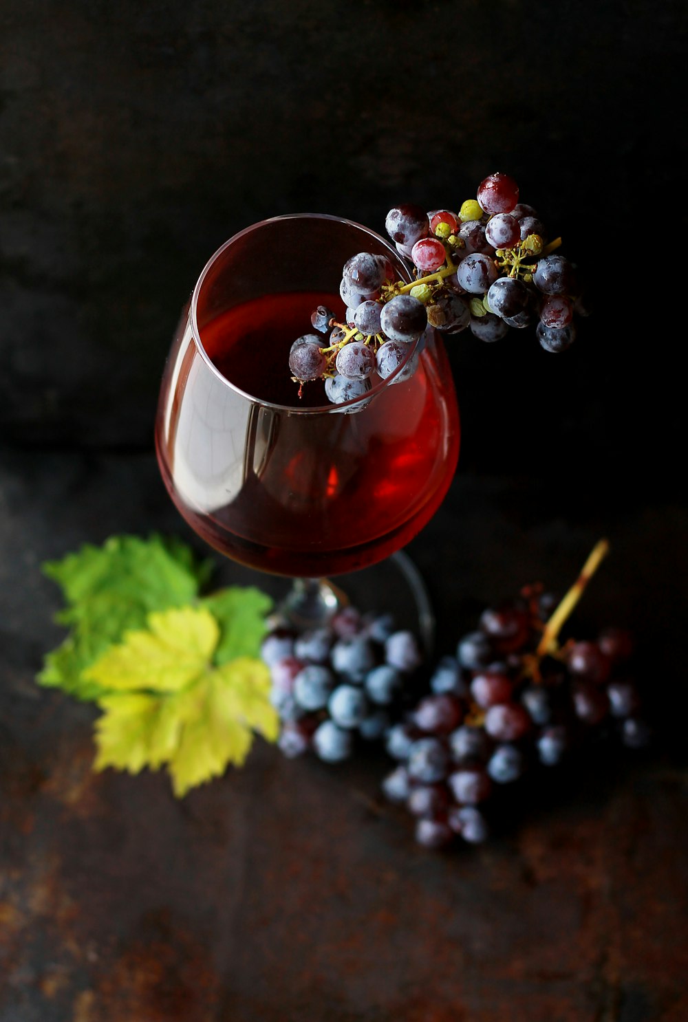 Macro view of a wine glass containing alcoholic wine with a bunch of grapes