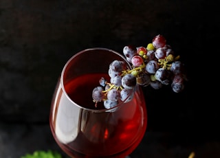 red grapes on clear glass wine