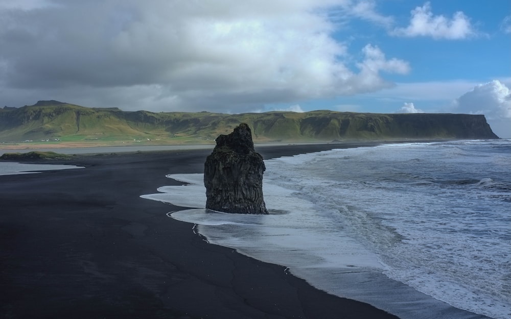 coastal rock on seashore under white clouds