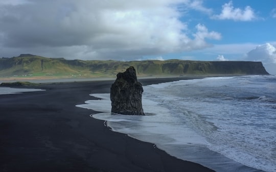 coastal rock on seashore under white clouds in Dyrhólaey Iceland