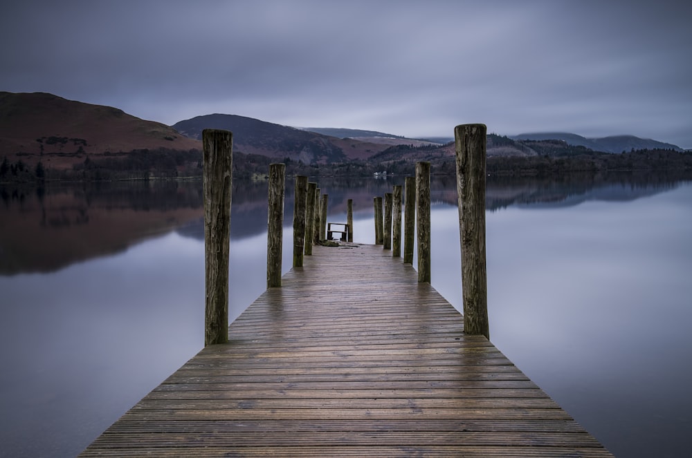 Pontile in legno marrone sullo specchio d'acqua che si affaccia sulle montagne