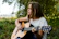 A joyful young woman playing guitar outdoors during a summer music workshop.