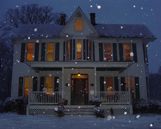 A cozy home with snow outside and warm light glowing from windows.