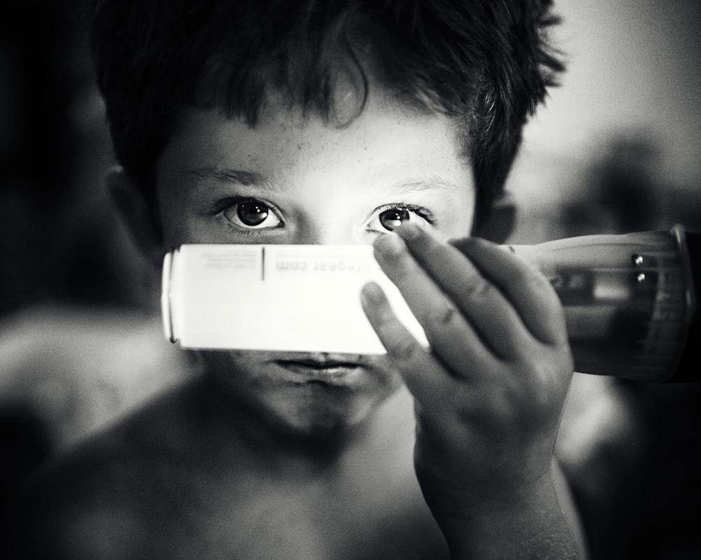 Foto en escala de grises de niño sosteniendo una bombilla