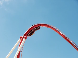 Close-up of a thrilling roller coaster twisting against a bright blue sky.