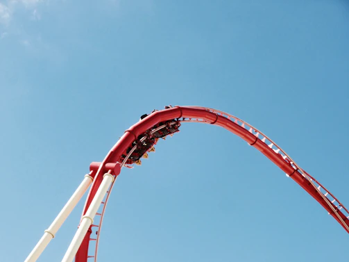 Close-up of a thrilling roller coaster twisting against a bright blue sky.