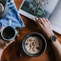 person holding blue ceramic mug and white magazine