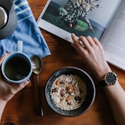 person holding blue ceramic mug and white magazine