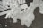 Bubbles and foam are spread unevenly over a dark surface, creating a textured pattern. The foam appears to be in various forms, with numerous small bubbles throughout, and is partially obscuring a geometric black and white design underneath.