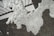 Bubbles and foam are spread unevenly over a dark surface, creating a textured pattern. The foam appears to be in various forms, with numerous small bubbles throughout, and is partially obscuring a geometric black and white design underneath.