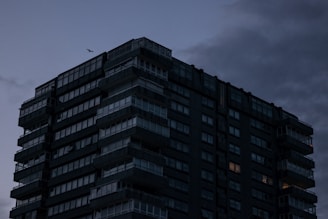 A sleek drone shot capturing a dark, high-luxury apartment building in Bogotá at dusk.