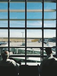 two men sitting in front of glass window during daytime