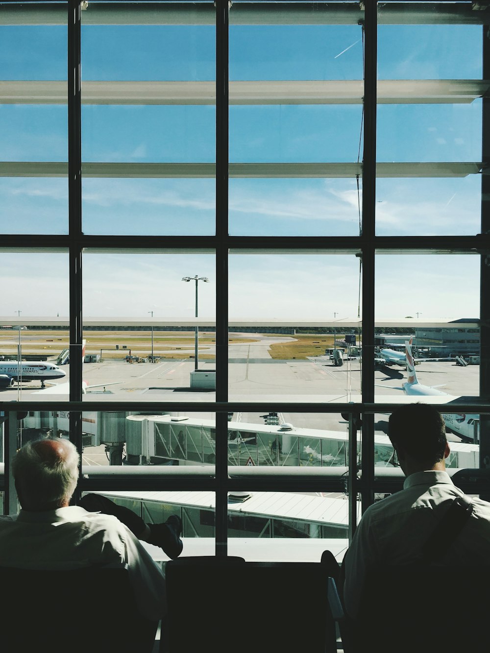 Dos hombres sentados frente a una ventana de vidrio durante el día