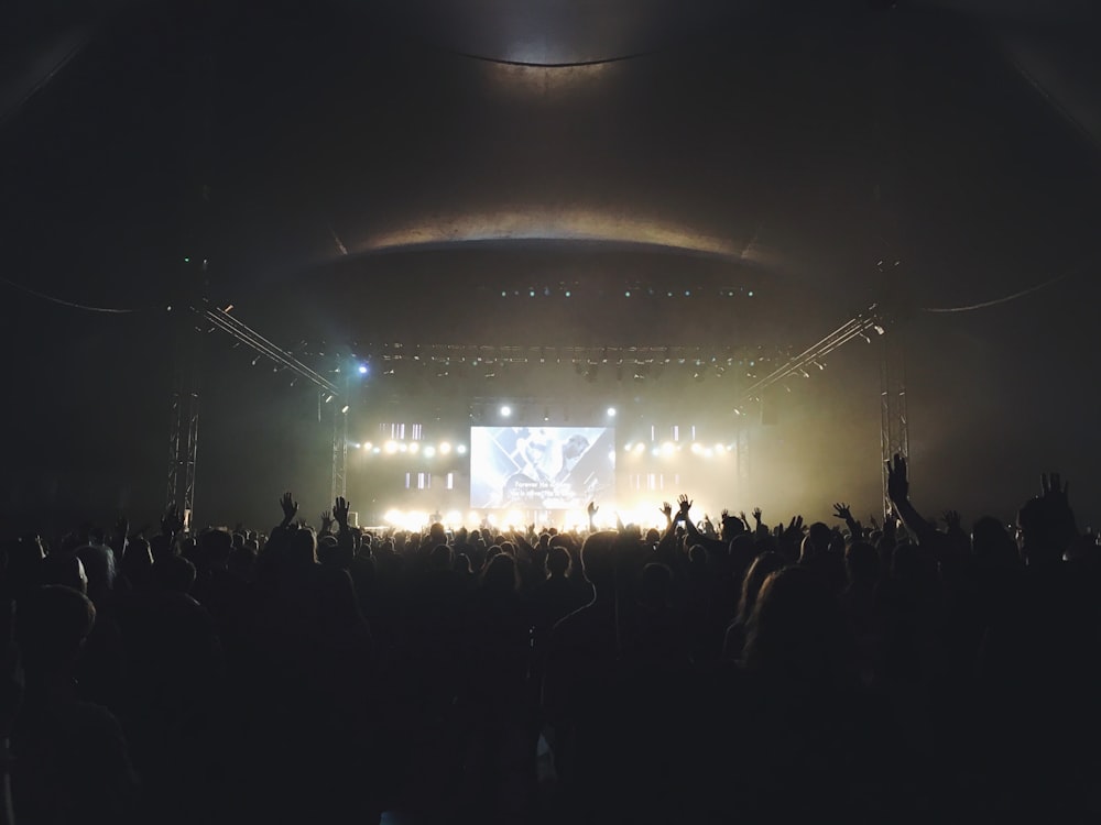 Multitud de pie cerca del escenario con la banda por la noche