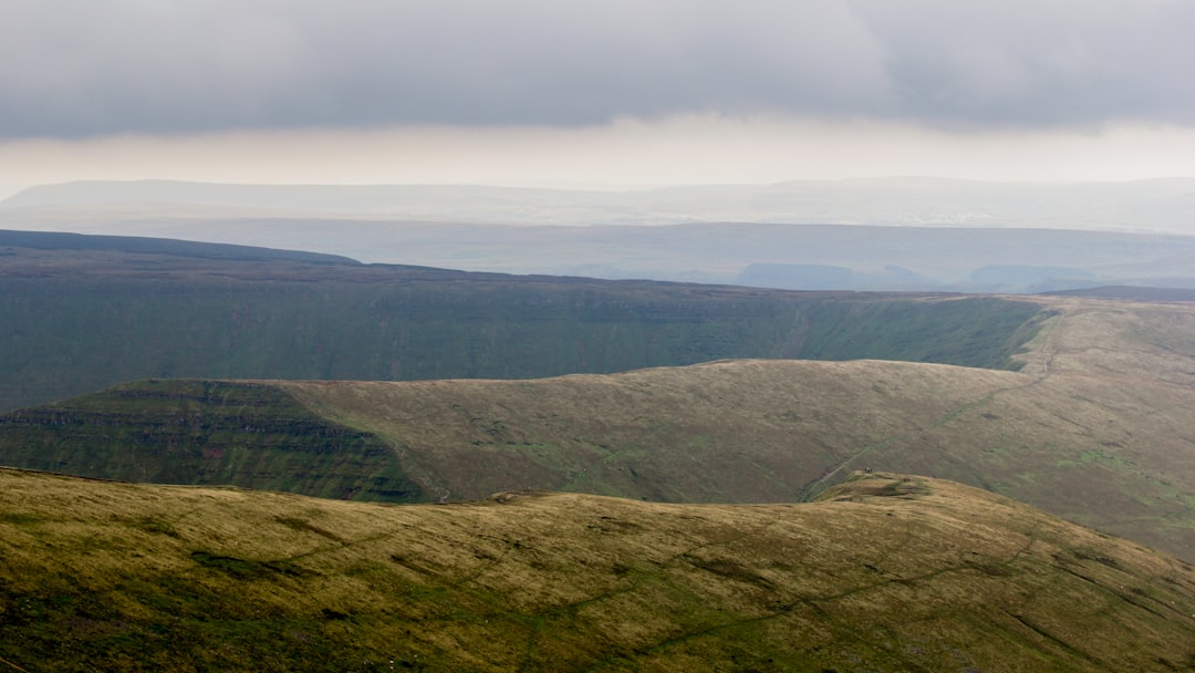 green grass covered mountain under white skies