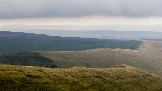 green grass covered mountain under white skies in Brecon Beacons United Kingdom