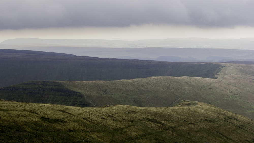 green grass covered mountain under white skies