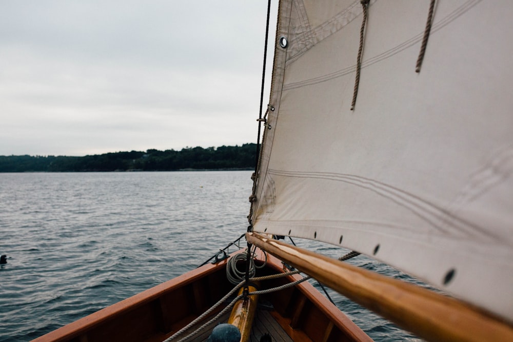 a sailboat with a white sail on a body of water