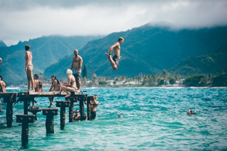 man diving from dock with people