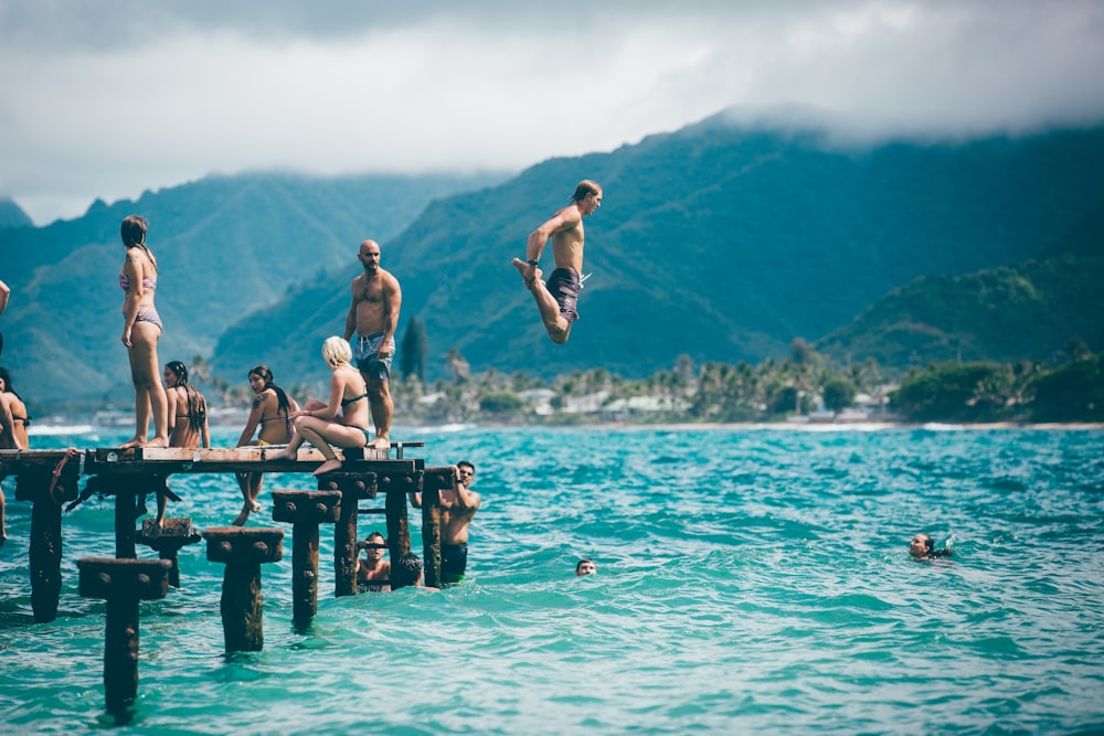 hombre buceando desde el muelle con la gente