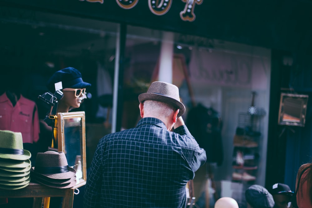 man holding his brown fedora hat facing backwards