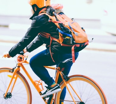 closeup photo of person riding a orange bicycle