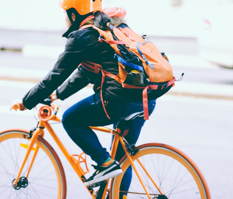 closeup photo of person riding a orange bicycle