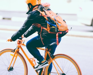 closeup photo of person riding a orange bicycle